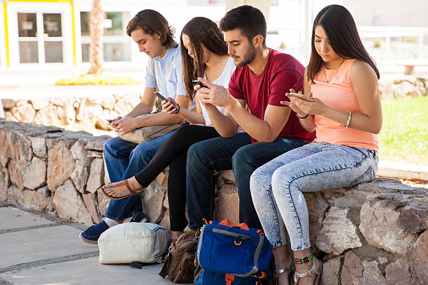 Group of Hispanic college students ignoring each other and using their cell phones